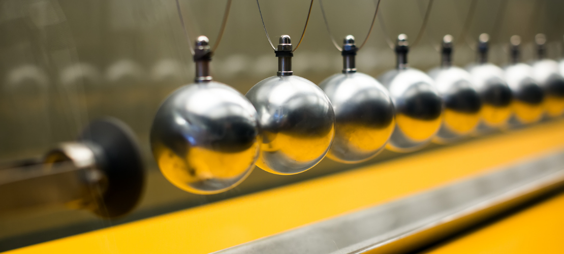 Row of polished steel balls hanging from wires, as in a collision balls demonstration of momentum