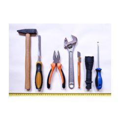 Hammer, chisel, pliers, adjustable wrench, a screwdriver, and other hand tools laid out above a tape measure on a white surface
